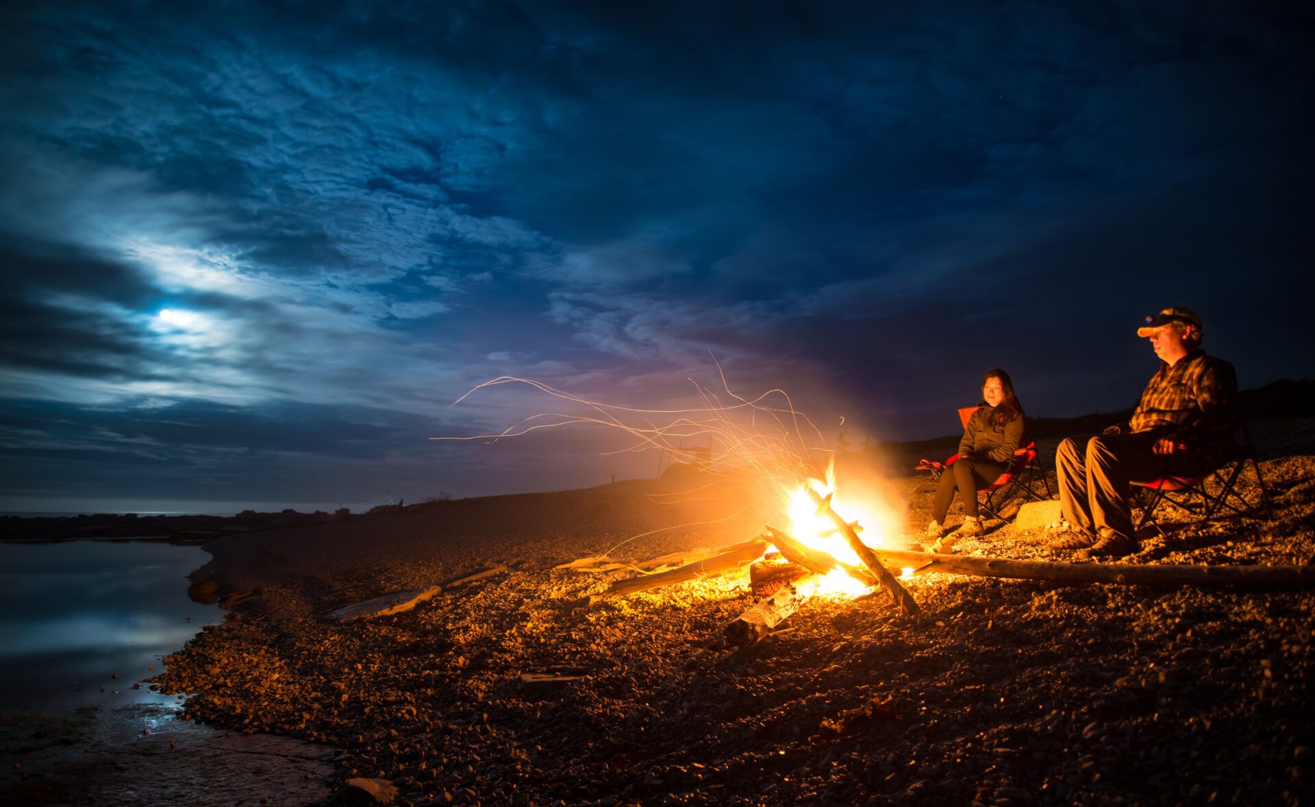 male-camper-looking-at -bonfire-on-hill